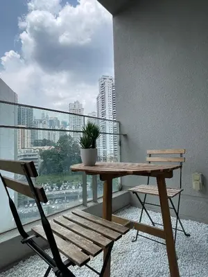 a wooden table and chair on a balcony with a window at The Robertson-Bukit Bintang by PILLOWTALKS in Kuala Lumpur