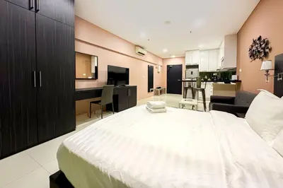 a bedroom with a large white bed and a living room at Summer Suites KLCC by apartx in Kuala Lumpur