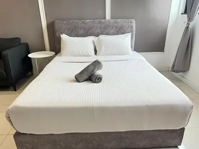 a large bed with a large white comforter with a rollerror at Chambers Residence by Gloria Homes in Kuala Lumpur