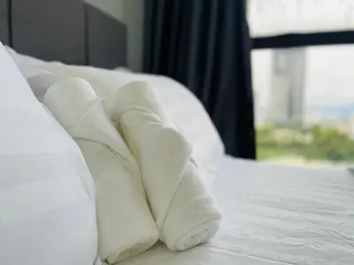 a pile of white towels laying on a bed at Arte Mont Kiara by DeUrban in Kuala Lumpur