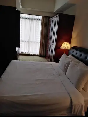 a bedroom with a large white bed with a lamp at Bukit Bintang Service Suite at Times Square in Kuala Lumpur