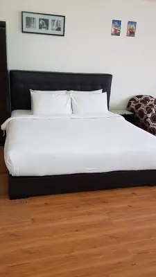 a bed with white sheets and pillows on a wooden floor at Bukit Bintang Service Suite at Times Square in Kuala Lumpur