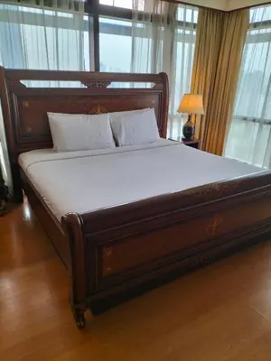 a large wooden bed in a room with windows at Bukit Bintang Service Suite at Times Square in Kuala Lumpur