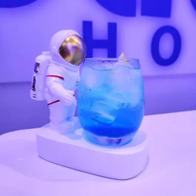 a figurine of an astronaut standing next to a blue drink at Space Hotel KL Sentral in Kuala Lumpur