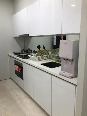 a kitchen with white cabinets and a sink and a microwave at Sky Suites at KLCC by Mitstay in Kuala Lumpur