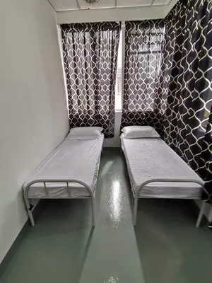 two empty beds in a room with a wall at Sri Rampai Metropolitan Hostel in Kuala Lumpur