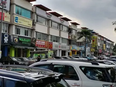 a parking lot with cars parked in front of a building at Sri Rampai Metropolitan Hostel in Kuala Lumpur