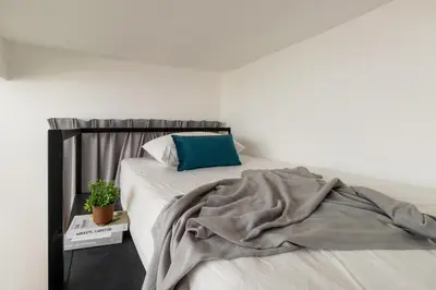 a white bedroom with a bed with a blue pillow at Upstairs Downstairs CoLiving Bukit Bintang in Kuala Lumpur