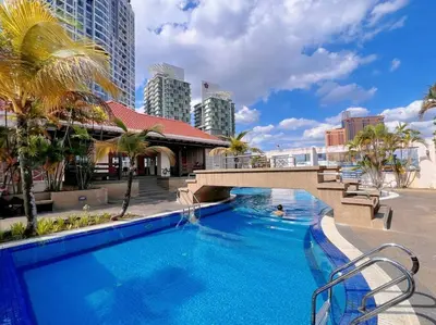 a large swimming pool with palm trees and buildings at Comfy Studio Casa Mutiara, Near LRT Hang Tuah & Lalaport in Kuala Lumpur