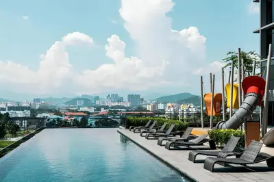 a pool on the roof of a building with lounge chairs at Expressionz KLCC By Sky Homez in Kuala Lumpur