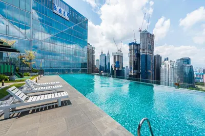 a swimming pool with chairs and a city skyline at Dorsett Residence Kuala Lumpur 8 pax in Kuala Lumpur