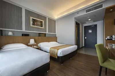 a hotel room with two beds and a chair at Hotel Transit Kuala Lumpur in Kuala Lumpur