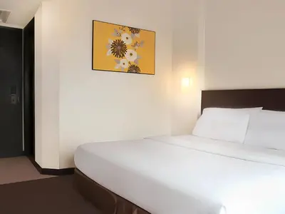 a bedroom with a white bed with a picture on the wall at Hotel Summer View in Kuala Lumpur