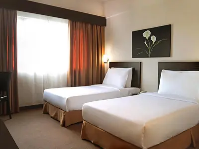 a hotel room with two beds and a window at Hotel Summer View in Kuala Lumpur
