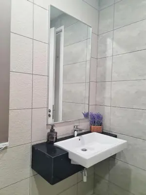 a bathroom with a white sink and a mirror at Muji Themed Apartment by Zen Sojourn - Opposite KL SENTRAL in Kuala Lumpur