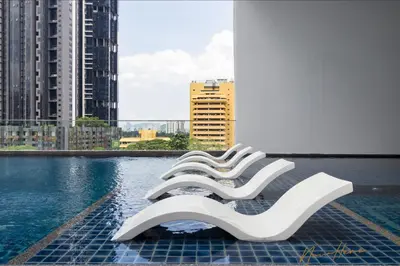 a row of white chairs sitting next to a pool at NowHere 2BR 4PAX with Balcony Reizz Jalan Ampang in Kuala Lumpur