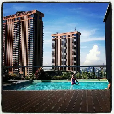 a woman in a swimming pool with buildings in the background at Bintang Fairlane Residence, Cozy Fam Suite with Bathtub - 2B2R in Kuala Lumpur