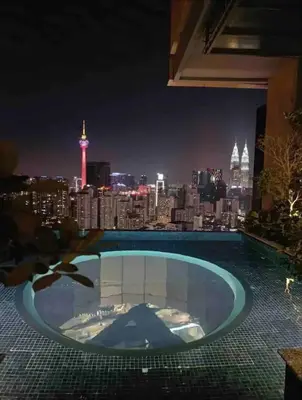 a swimming pool with a view of the city at night at Maxhome Elite at Lucentia in Kuala Lumpur
