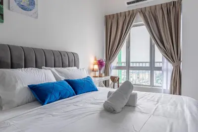 a white bed with blue pillows and a window at 5min to KL TRX Bukit Bintang for 6paxs in Kuala Lumpur