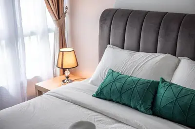 a bed with a green pillow and a lamp on a table at 5min to KL TRX Bukit Bintang for 6paxs in Kuala Lumpur
