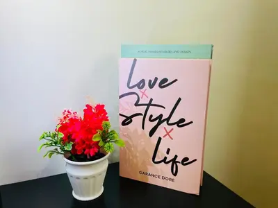 a book and a vase with flowers on a table at EST Bangsar KL Sentral by DeUrban in Kuala Lumpur