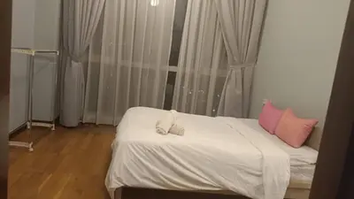 a bedroom with a bed with white sheets and pink pillows at Regalia Suite 12-13 in Kuala Lumpur