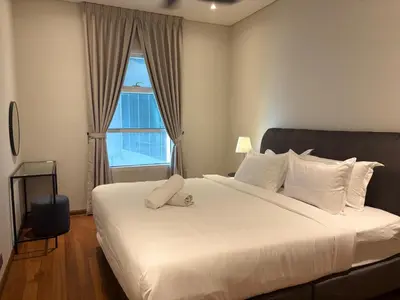 a bedroom with a large white bed with a window at SkySuites Luxury Suite By CalmSojourn in Kuala Lumpur