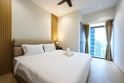 a bedroom with a large white bed and a window at Eaton Residence KLCC by GB in Kuala Lumpur