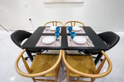 a black table with four chairs and a table with plates at Eaton Residence KLCC by GB in Kuala Lumpur