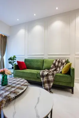 a green couch in a living room with windows at Eaton Residence KLCC by GB in Kuala Lumpur