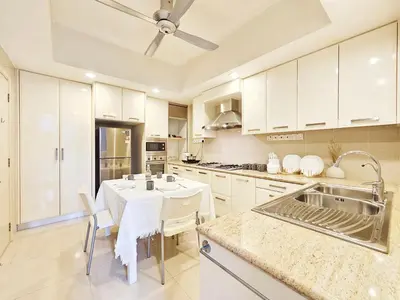 a kitchen with white cabinets and a white table at Fahrenheit Bukit Bintang Big Group 13Pax Family Suites in Kuala Lumpur
