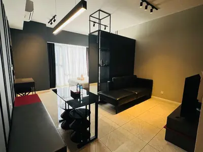 a living room with a black couch and a glass table at AXON Residences Kuala Lumpur in Kuala Lumpur