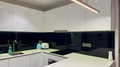 a kitchen with white cabinets and black and white counters at Star Xtian Apartment KLCC in Kuala Lumpur
