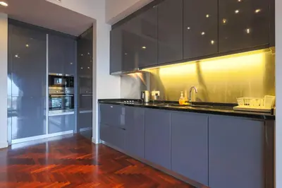 a kitchen with black cabinets and a wooden floor at The Mews KLCC by GB in Kuala Lumpur