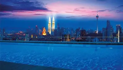 a swimming pool with a city skyline at night at Regalia Infinity Skypool in Kuala Lumpur