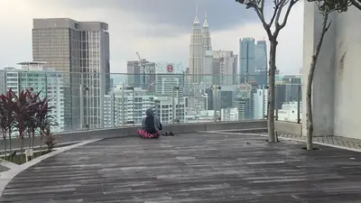 a person sitting on a ledge looking at a city skyline at Balcony Cityscape III The Robertson Residence 41f in Kuala Lumpur