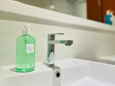 a glass soap bottle sitting on a bathroom sink at Arcoris Residence Mont Kiara by DeUrban in Kuala Lumpur