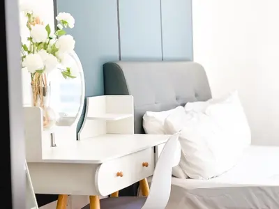 a white bedside table with a mirror next to a white bed at Una Serviced Apartment by Manhattan Group in Kuala Lumpur