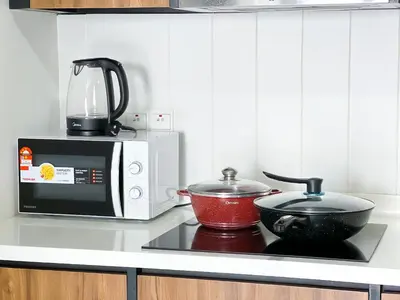 a kitchen with a stove with a microwave and a pot at Una Serviced Apartment by Manhattan Group in Kuala Lumpur