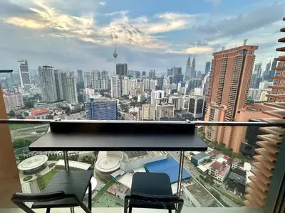 a balcony with two chairs and a view of a city at 1BR condo with Amazing KLCC View & Infinity Pool at Lalaport Bukit Bintang in Kuala Lumpur