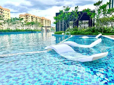 a swimming pool with two white chairs in the water at KL Central 33rd Floor KLCC view in Kuala Lumpur