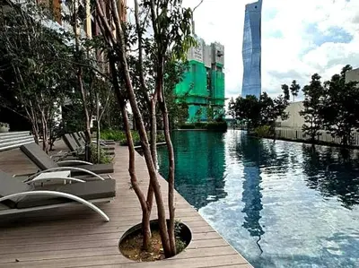 a pool with a palm tree next to a building at Studio with Amazing KLCC View & Infinity Pool at Lalaport Bukit Bintang in Kuala Lumpur