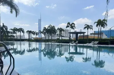 a large swimming pool with palm trees and a city at Cozy studio service suite Free parking Netflix Trion B5206 KL in Kuala Lumpur