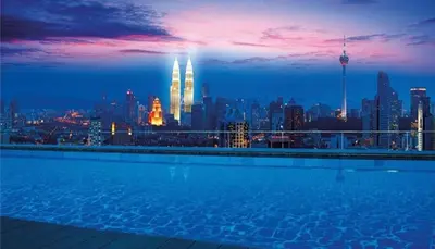 a swimming pool with a city skyline at night at KL Infinity Pool Hostel in Kuala Lumpur