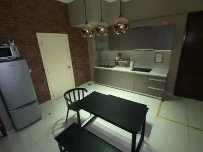 a kitchen with a table and a chair and a refrigerator at KL Infinity Pool Hostel in Kuala Lumpur