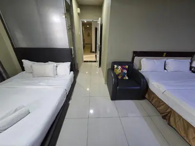 a room with two beds and a chair in it at Hotel AL Amin By Ahmed in Kuala Lumpur