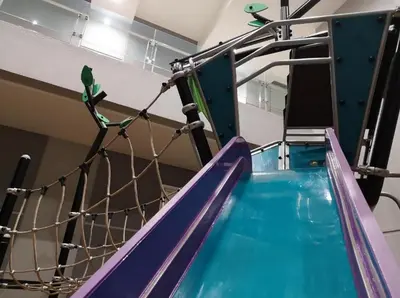 a green parrot perched on top of a slide at Pool World at Robertson Residence Kuala Lumpur in Kuala Lumpur