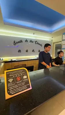 two men standing in front of a counter with a sign at South of The Clouds HOTEL KL Sentral \u5409\u9686\u5761\u5f69\u4e91\u4e4b\u5357\u9152\u5e97-\u4e2d\u592e\u8f66\u7ad9\u5e97 in Kuala Lumpur