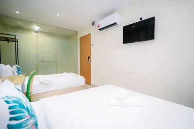 a room with two beds and a tv on the wall at Swing & Pillows - Times Square, Bukit Bintang in Kuala Lumpur