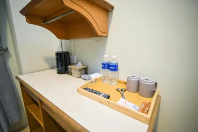a wooden tray with water bottles and cups on a counter at Swing & Pillows - Petaling Street Kuala Lumpur in Kuala Lumpur